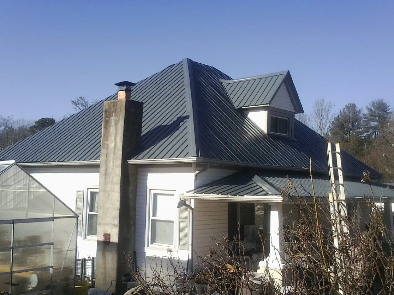 Dark blue standing seam metal roof on a white farmhouse with dormer — Slate & Tile Roof Repair by Roofing Brothers in Dacono