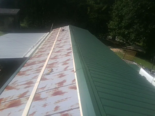 Old rusted panels beside newly installed green metal roofing — Wind Damage Roof Repair by Roofing Brothers in Dacono
