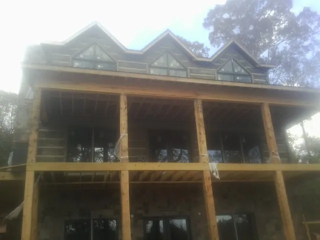Dormers and porch framing on a large log home under construction — Roof Coating work by our crew in Dacono