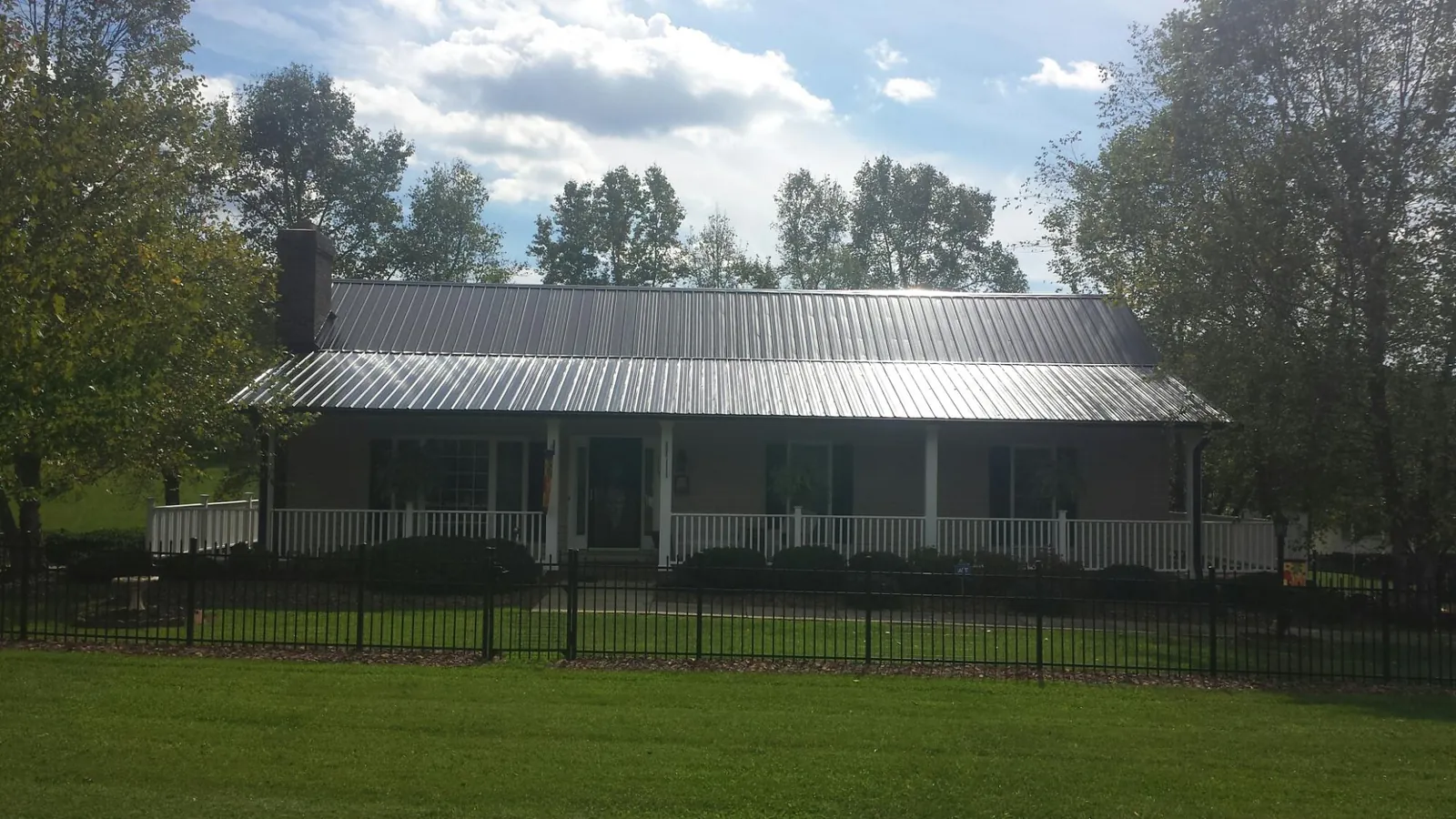 Gray metal roof on a brick ranch with a full width front porch — Gutter Guard Installation work by our crew in Dacono