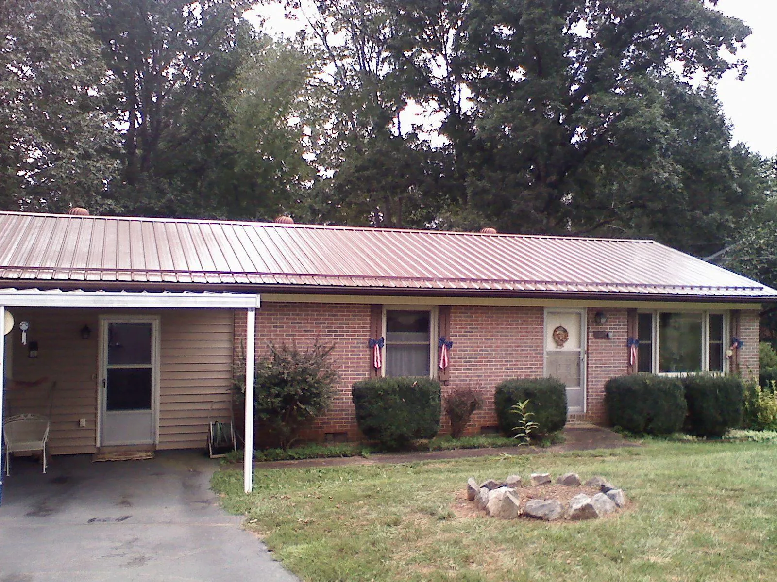 Bronze metal roof and carport on a brick ranch home — Roof Repair work by our crew in Dacono