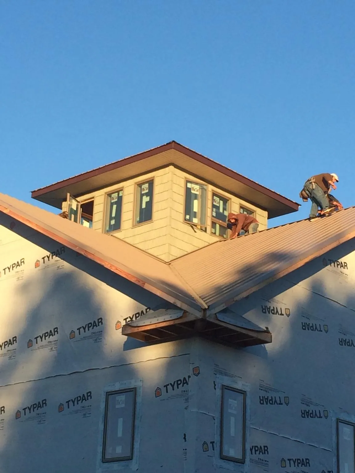 Roofers working around a rooftop cupola on a new metal roof at sunset — Roof Waterproofing in Dacono by Roofing Brothers